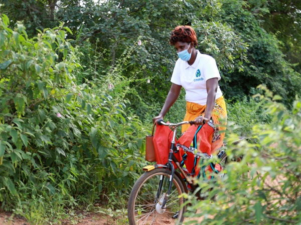 A community health worker wearing a face mask on a bicycle in Kenya in 2021.