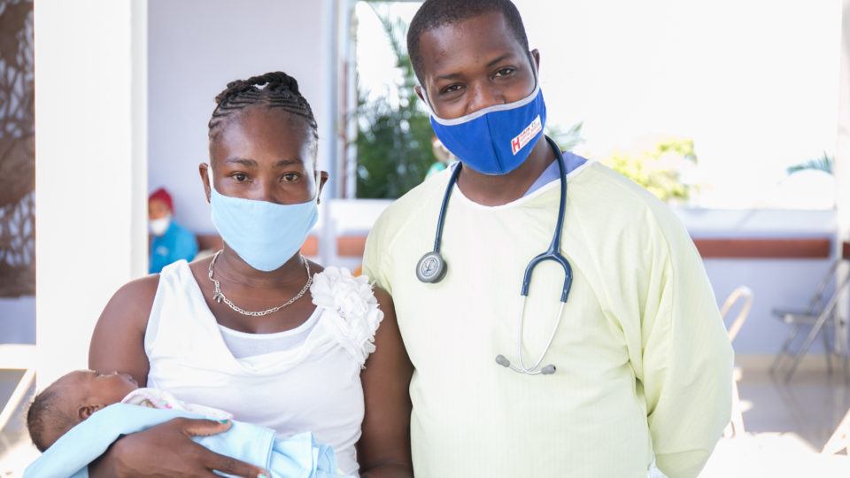 A mother holding her newborn infant with a doctor at Bisop Joseph Sullivan Center for Health hospital in Haiti in 2020.