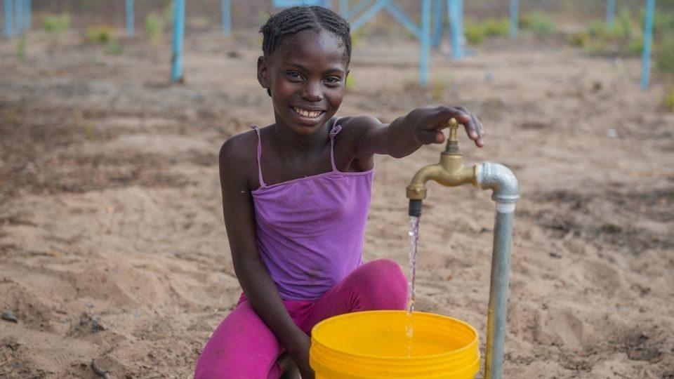 A young girl uses a borehole at her primary school in Zambia