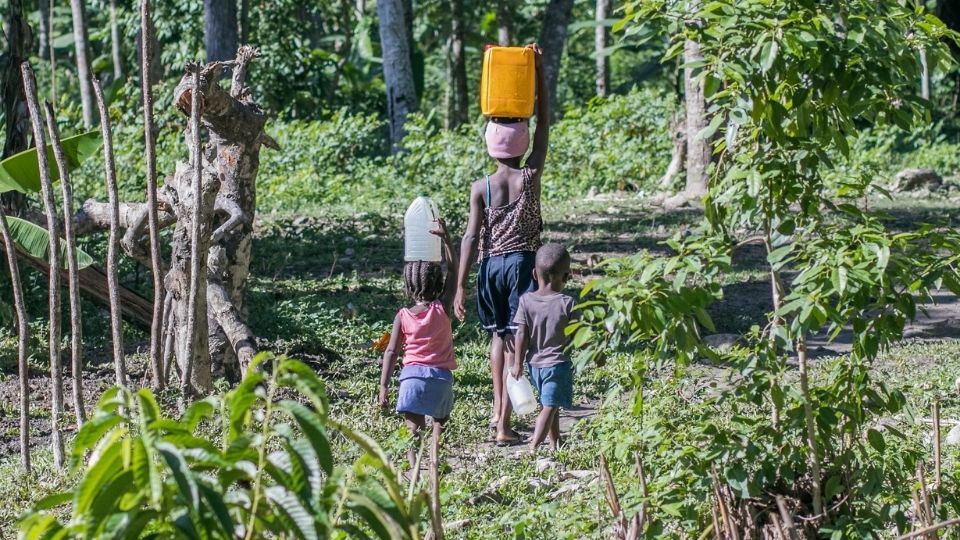 A woman and her children walk to collect water in Haiti