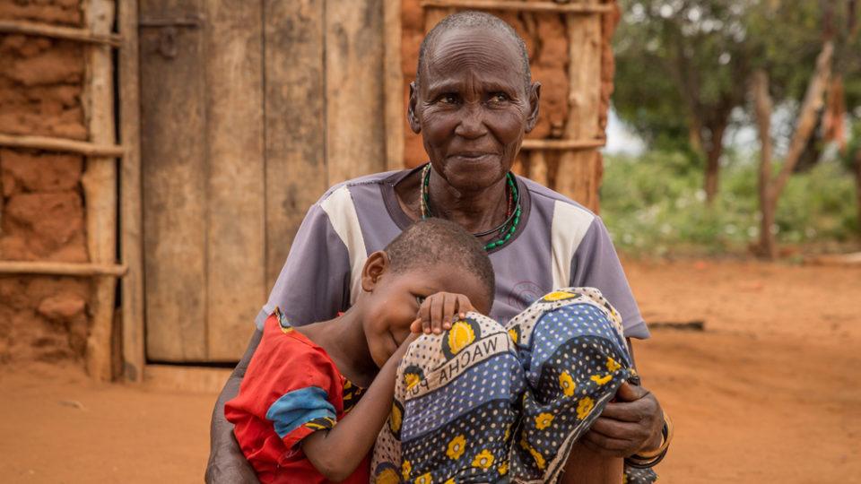 A grandmother sitting with her grandchild before their home in Mutomo, Kenya.
