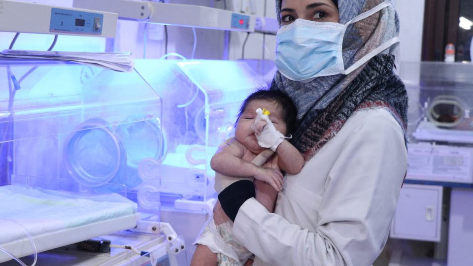 A health worther at Al-Rahma Hospital in northwest Syria hold a newborn infant in 2021.