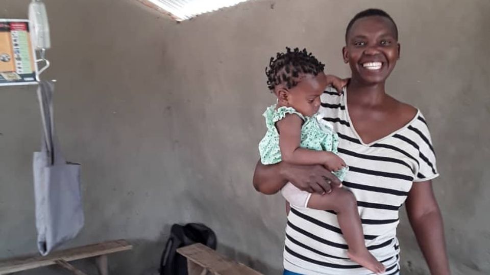 Ms. Mabuku holds her child while being visited by a CHW