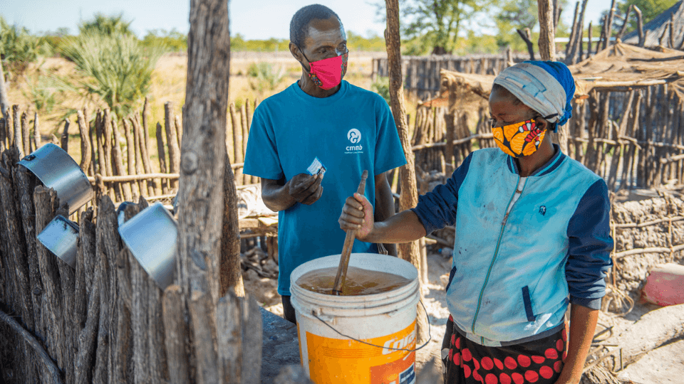 community health worker and woman purifying water