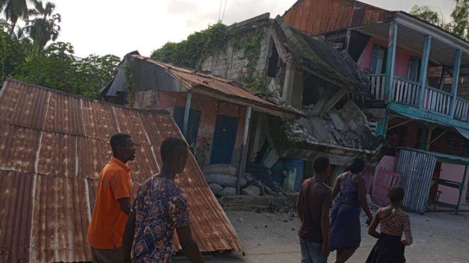 people walking near collapsed buildings after earthquake in haiti