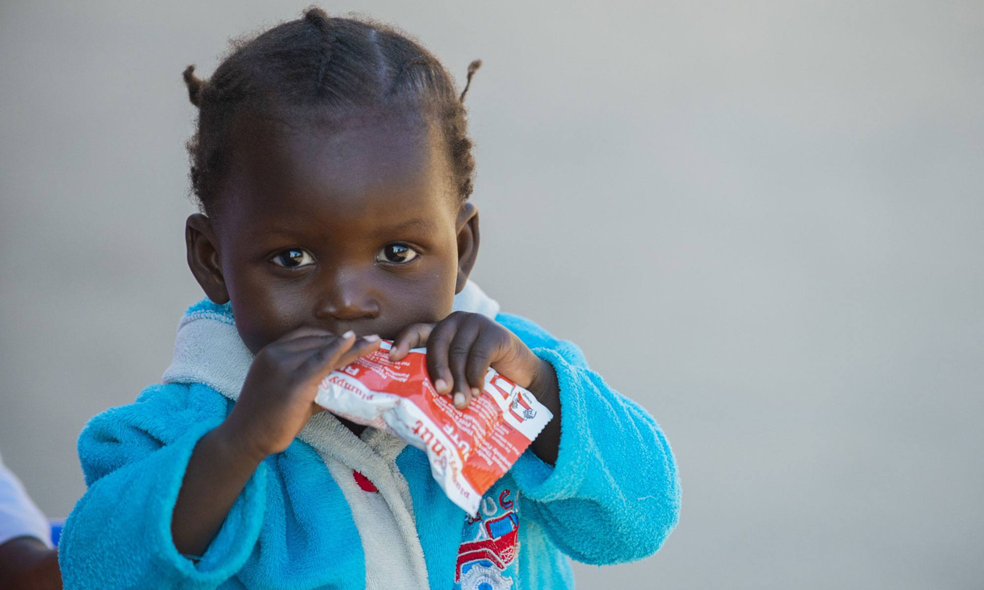A child eating a nutritional Plumpy'Nut in Zambia in May 2021.