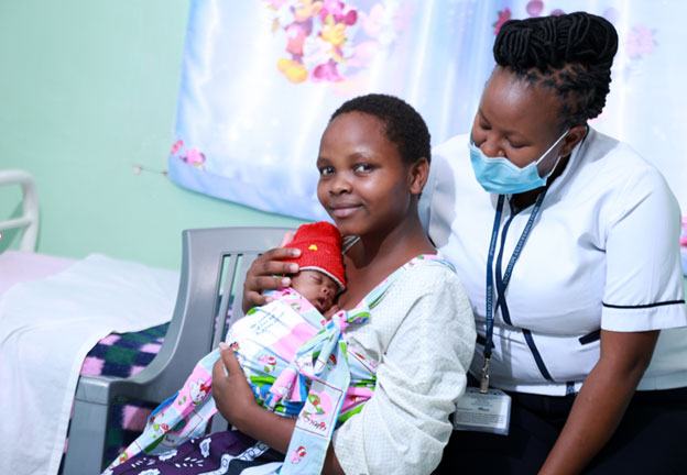 A mother holding her newborn with a healthcare worker in Kenya.