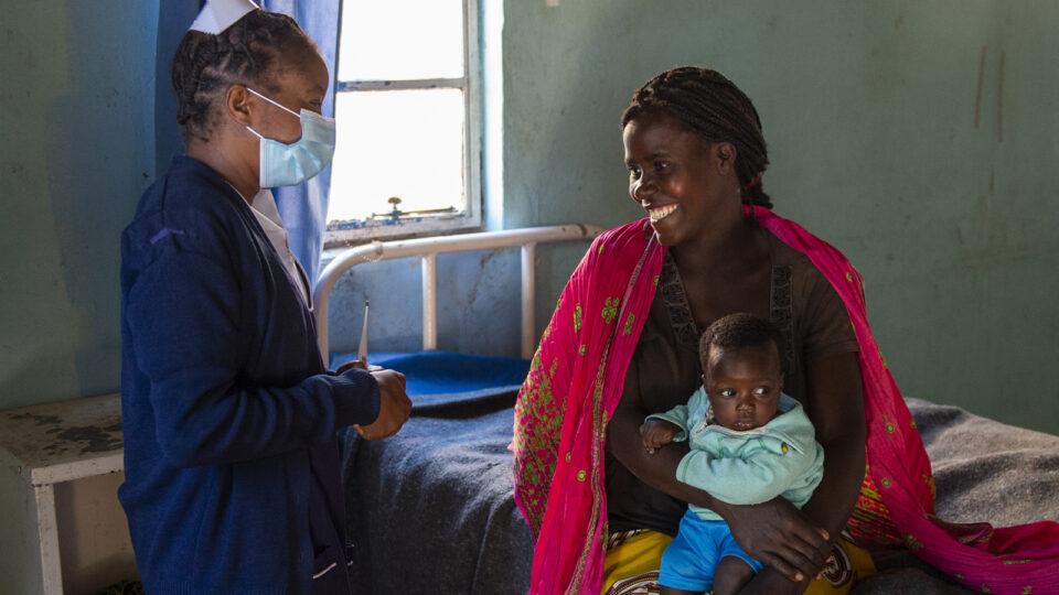 A community health worker with a mother and child at a health facility in Zambia in May 2021.