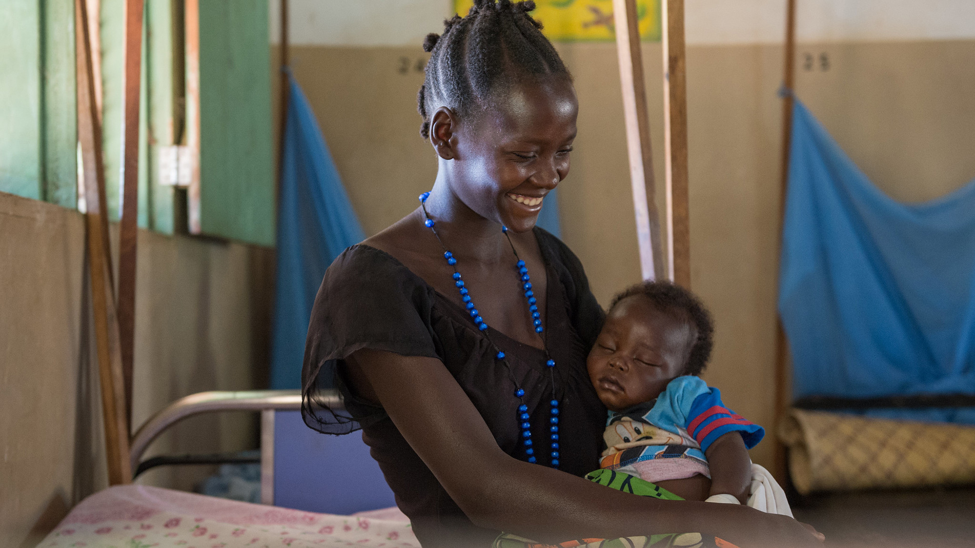 A mother smiles at her baby while receiving care at a health facility_South Sudan_July2022