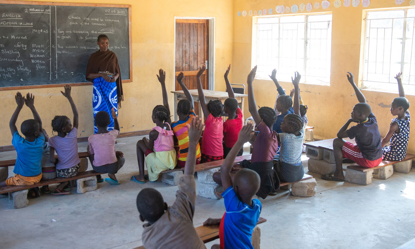 students raise their hands in the classroom in Zambia_Aug2022