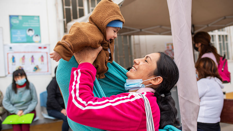 A mother in Peru holds up her smiling baby_Sept2022