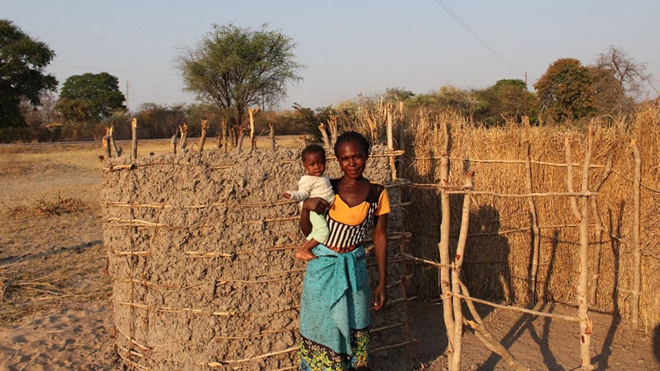 Mom and Baby in front of a household latrine_Zambia_Sept2022