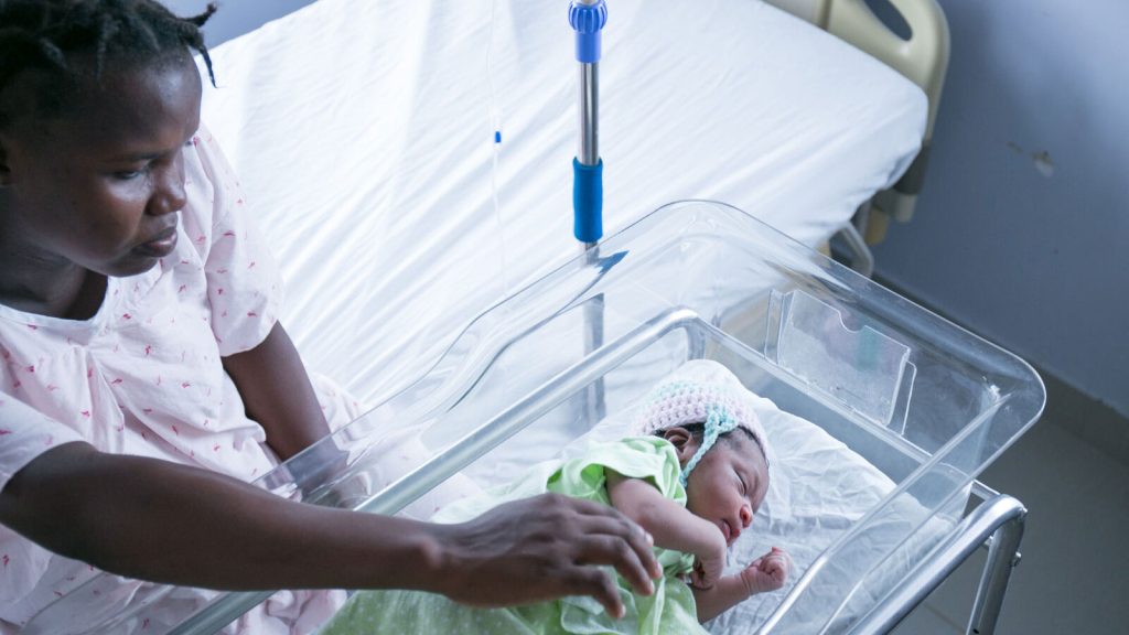 A mother looks over her baby who is resting at the hospital. 