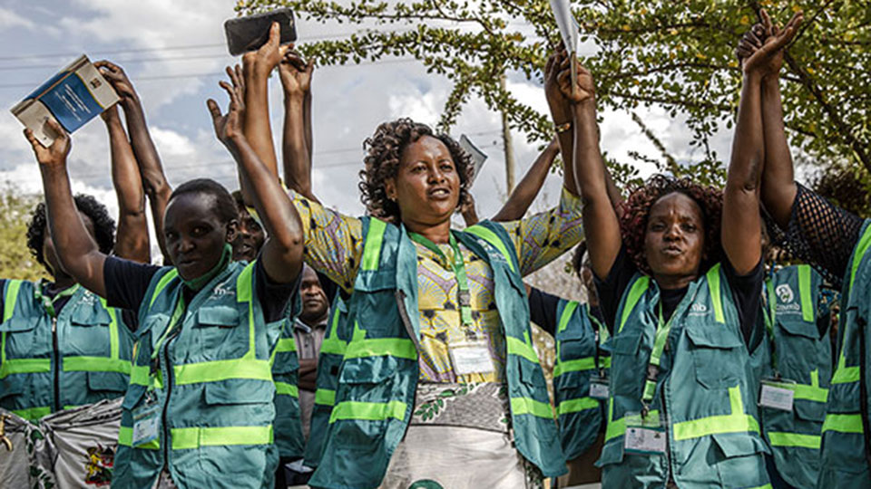 community health promoters in Kenya celebrate with their hands in the air. 