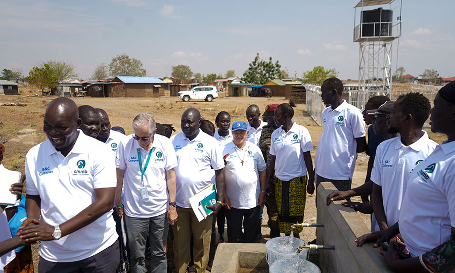 Attendees of a water yard ceremony stand around a water collection point.