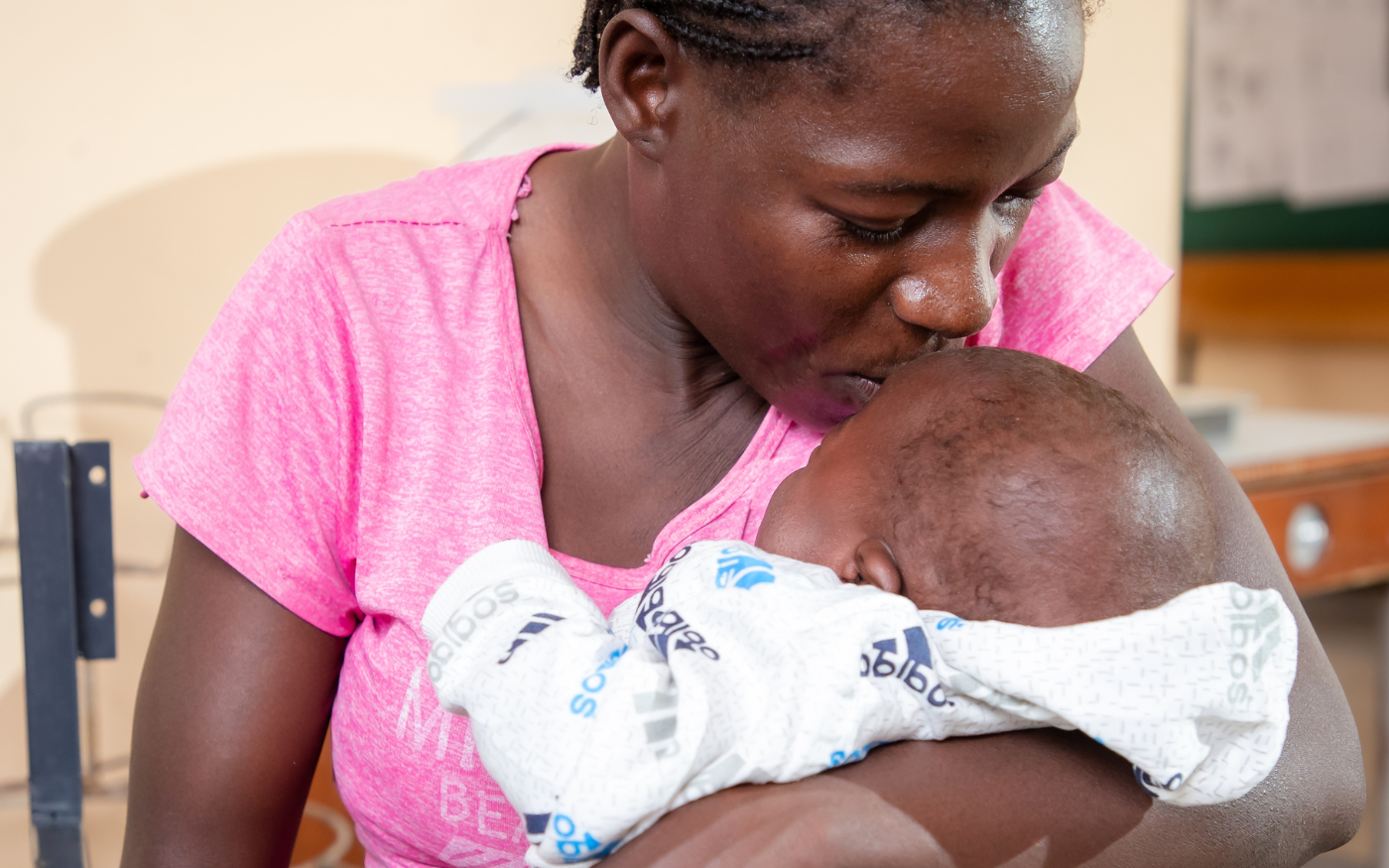 A mother kisses her newborn on the forehead