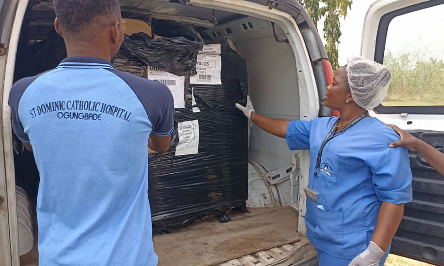 Staff from St. Dominic's stand behind a delivery truck with donated medicines from CMMB.