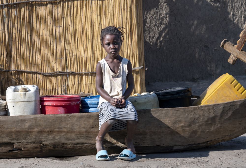 a child in Zambia sits on a wooden seat in