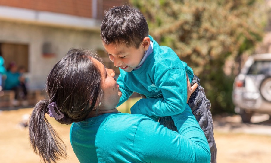 a mother holds her child up in her arms.